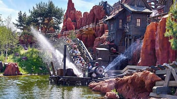 Une attraction aquatique avec une structure en bois, un petit bâtiment et un terrain rocheux.