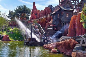 A water ride with a wooden structure, a small building, and rocky terrain.