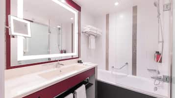 Une salle de bain moderne avec un grand miroir, deux lavabos, une baignoire et une douche.