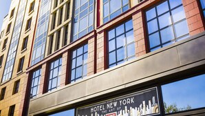 Un edificio de hotel de varios pisos con grandes ventanales y un cartel que indica que es el Hotel New York.