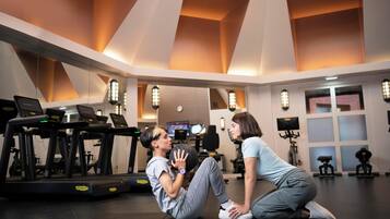 A gym with treadmills, exercise balls, and a person performing a sit-up with another person.