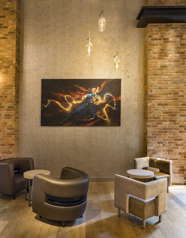 A modern lounge area with a large abstract painting, leather seating, and exposed brick walls.