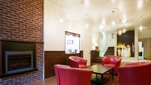 A modern living room with a brick fireplace, red leather chairs, and a wooden coffee table.
