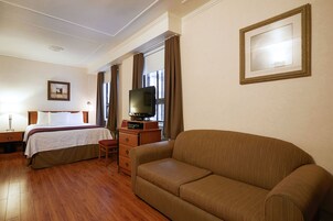 Une chambre d’hôtel comprenant un lit, un canapé, une télévision et une commode.