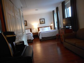 A hotel room with two beds, a desk, a television, and a sofa.