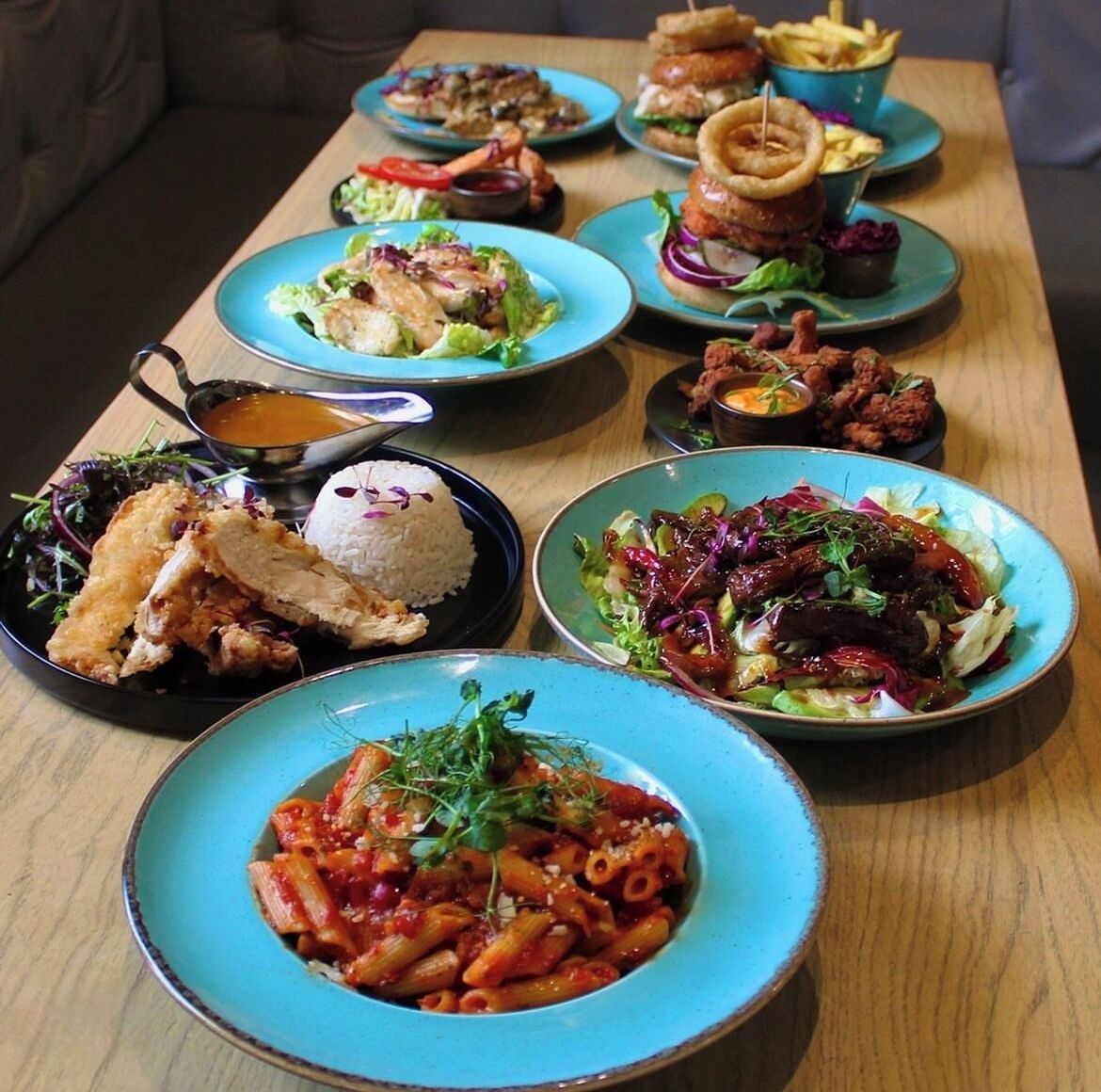Variedad de platos sobre una mesa de madera, como pasta, ensaladas y pan.