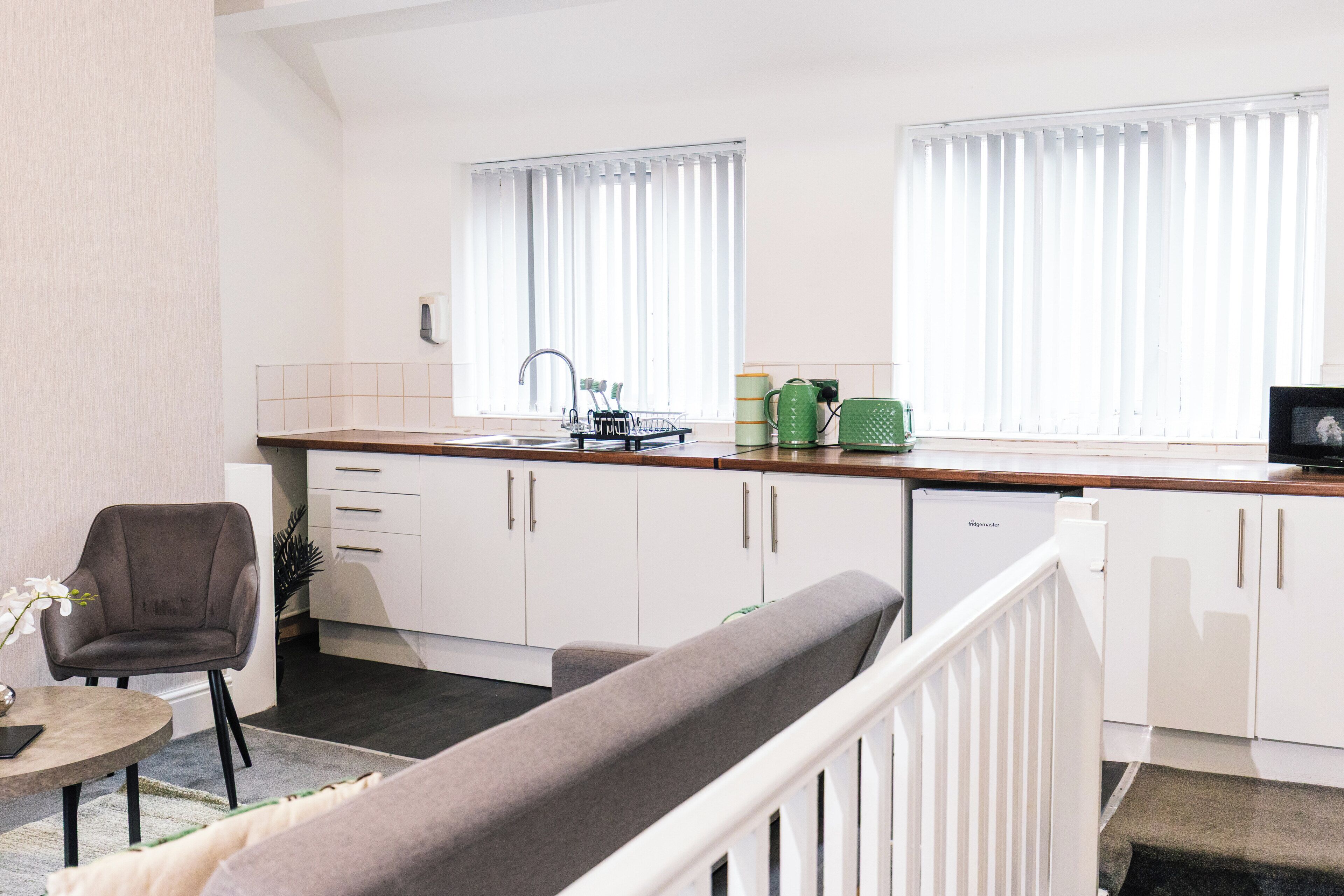 A modern kitchen with white cabinets, a sink, and a window with blinds.