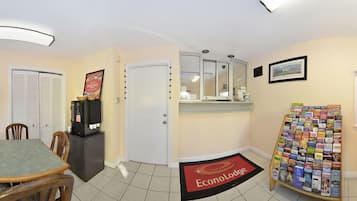 Eine Hotelhalle mit Essbereich, einer Kaffeemaschine, einer Auswahl an Reiseführern und einer Tür zu einem Zimmer.