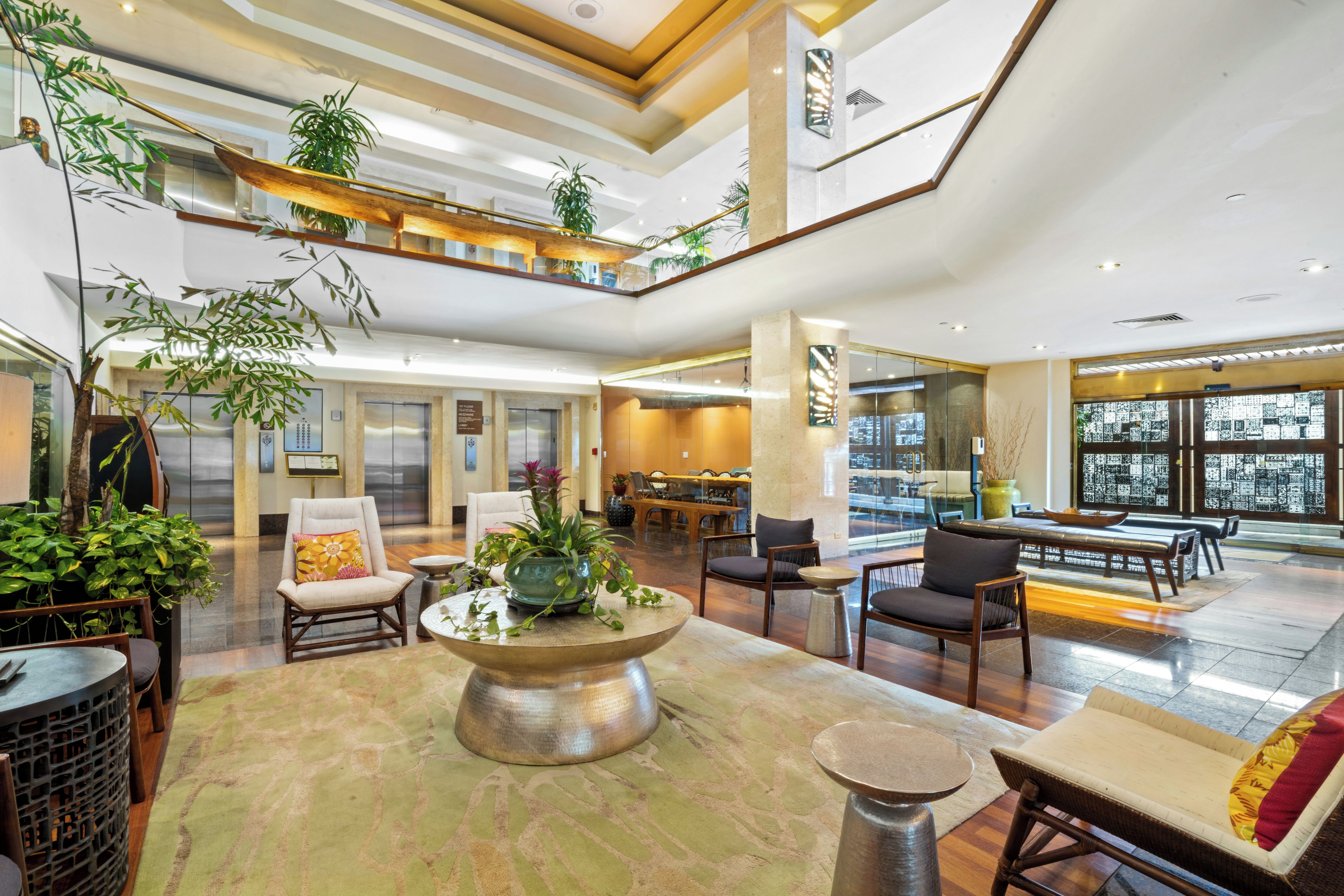 A spacious lobby with multiple seating areas, a central decorative table, and a high ceiling with natural light.