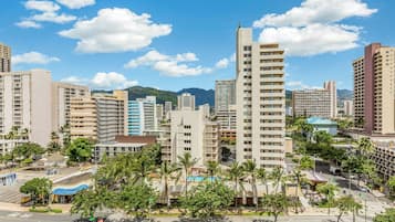 A high-rise building with multiple floors, surrounded by other buildings and palm trees.