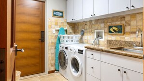 A laundry area with a washing machine, a sink, and cabinets. - Luana Waikiki Hotel & Suites (Honolulu)