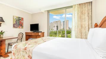 Habitación de hotel con cama, escritorio, televisor y ventana con vista a la ciudad.