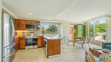 A modern kitchen with stainless steel appliances, a dining area with a view, and a living space with a sofa.