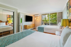 A hotel room with a large bed, a smaller bed, a TV, a cabinet, and a view of the outdoors. - Luana Waikiki Hotel & Suites (Honolulu)