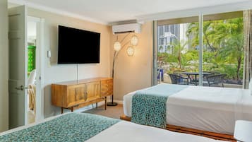 A hotel room with two beds, a TV, a cabinet, and a view of palm trees.