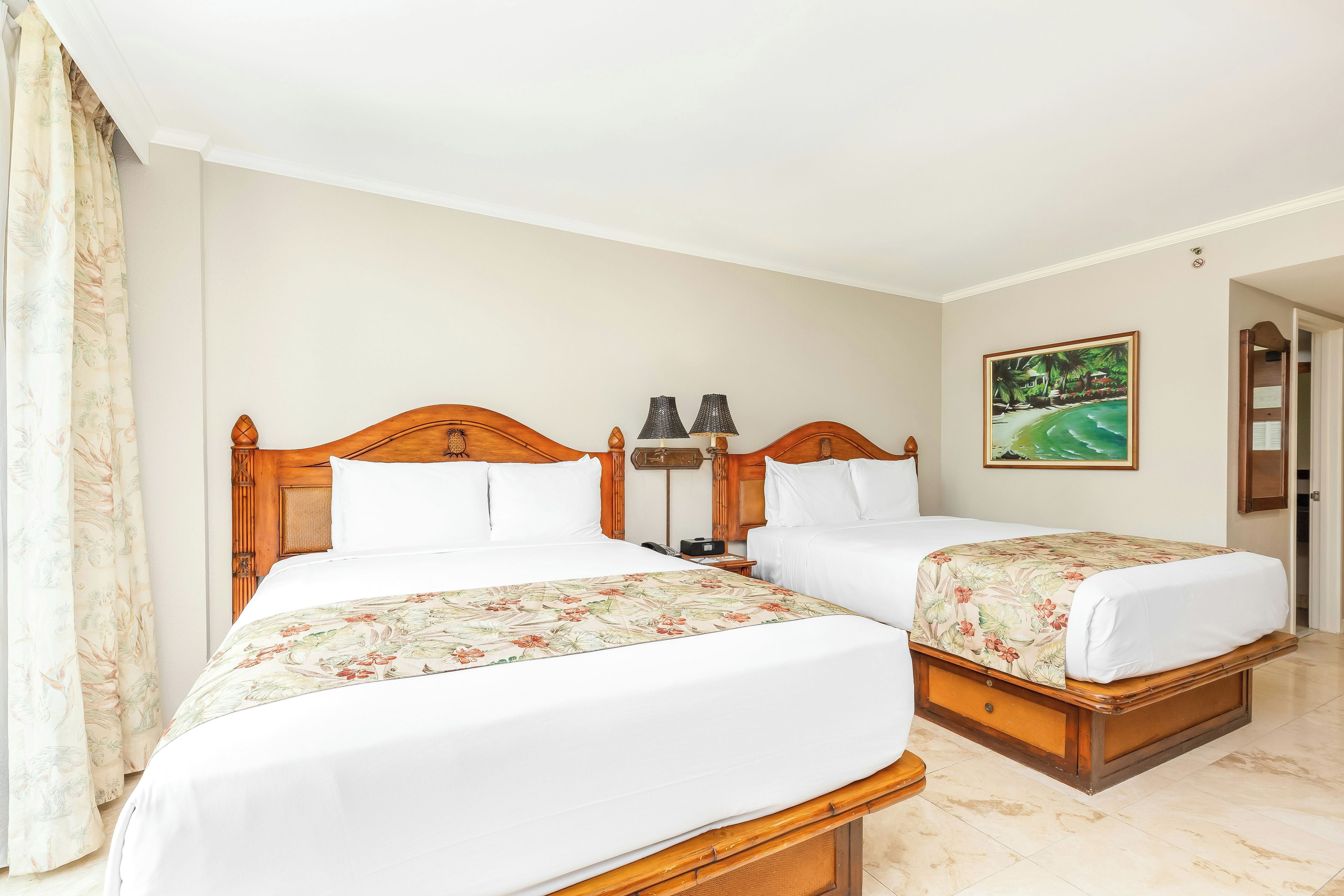 A hotel room with two wooden beds, white bedding, a painting on the wall, and a door leading to another room.