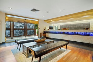A modern interior with a seating area, a reception desk, and a view through large windows.