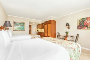 Habitación de hotel con dos camas, un armario de madera, una mesa de comedor con sillas y un cuadro en la pared.