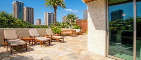 A rooftop patio with stone flooring, outdoor seating, and a city skyline view.