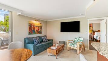 A living room with a sofa, coffee table, TV, and a dining area.