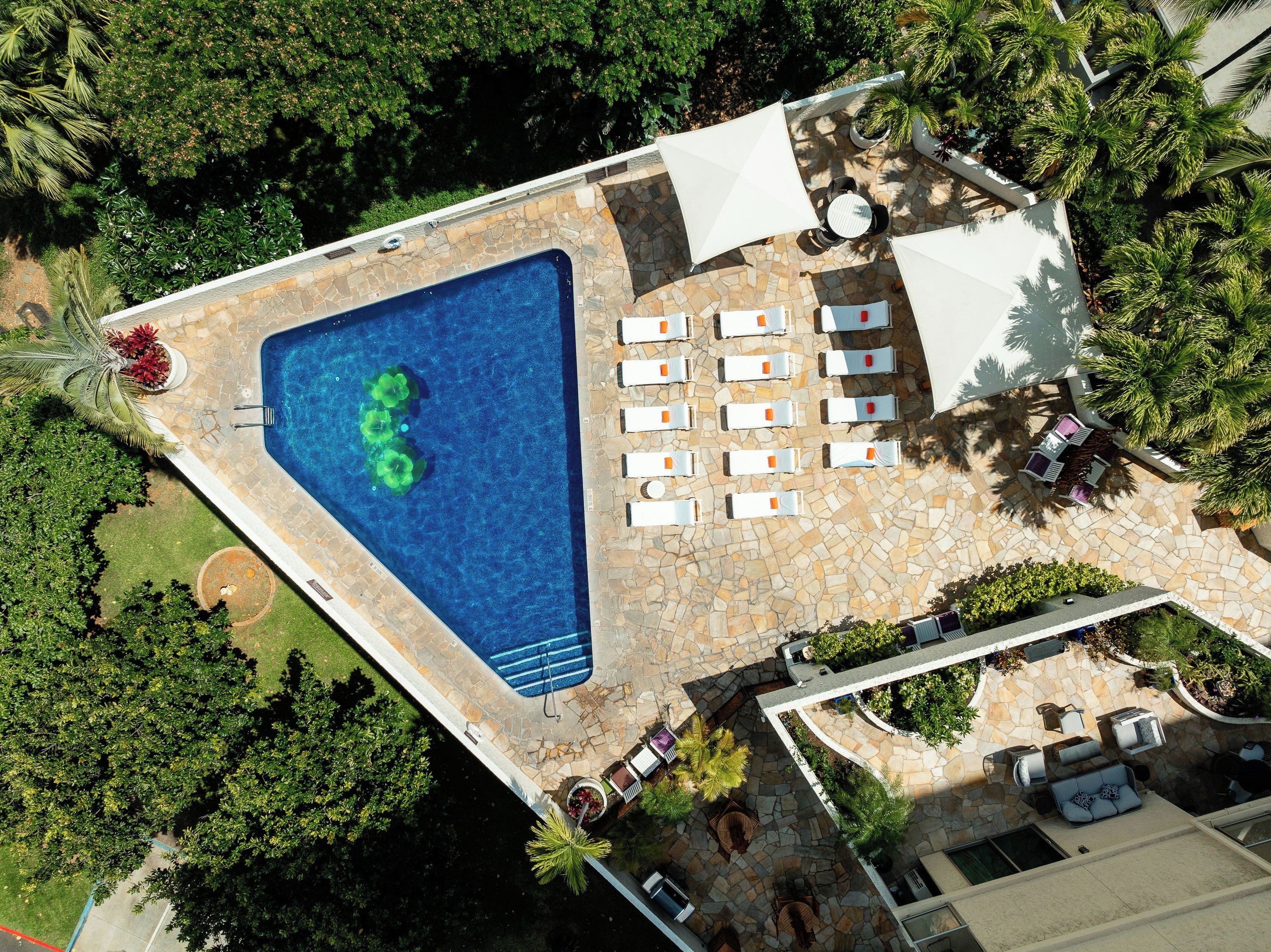An aerial view of a swimming pool area with lounge chairs and a stone patio.