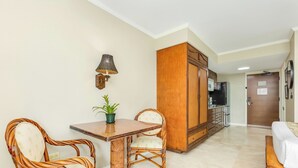 Une pièce comprenant une table à manger, deux chaises, une plante en pot, une armoire et un coin cuisine.