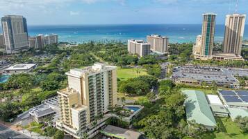 A high-rise hotel with multiple floors, a parking lot, and a view of the ocean.