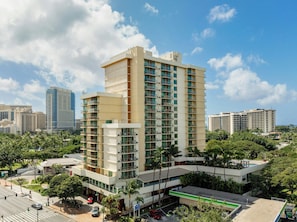 A multi-story hotel with a modern design, featuring balconies and a rooftop pool area.