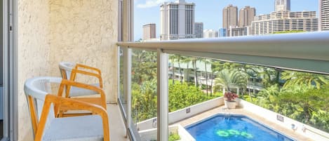 Un balcón con vista a una piscina y al paisaje urbano.