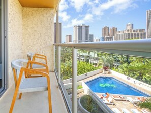 A balcony with a view of a swimming pool and cityscape.