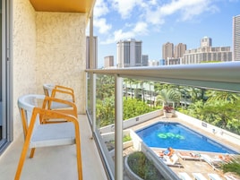 Un balcón con vista a una piscina y al paisaje urbano.