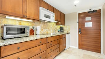 A kitchen with wooden cabinets, a built-in microwave, a toaster oven, and a coffee maker.