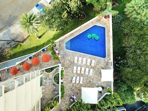 A rooftop pool area with lounge chairs and umbrellas, surrounded by greenery. - Luana Waikiki Hotel & Suites (Honolulu)