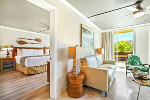 A hotel room with a bed, a sitting area with a sofa and armchairs, a dining table, and a view of the outdoors. - Luana Waikiki Hotel & Suites (Honolulu)