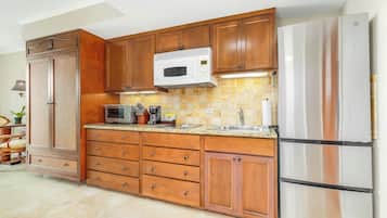 A kitchen with wooden cabinets, a microwave, a refrigerator, and a tiled backsplash.