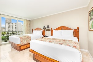 A hotel room with two beds, a large window with a city view, and a painting on the wall.