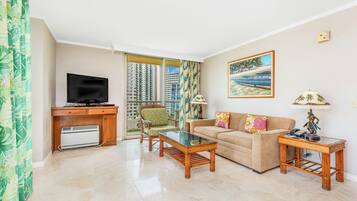 A living room with a flat-screen TV, a sofa, a coffee table, and a lamp.