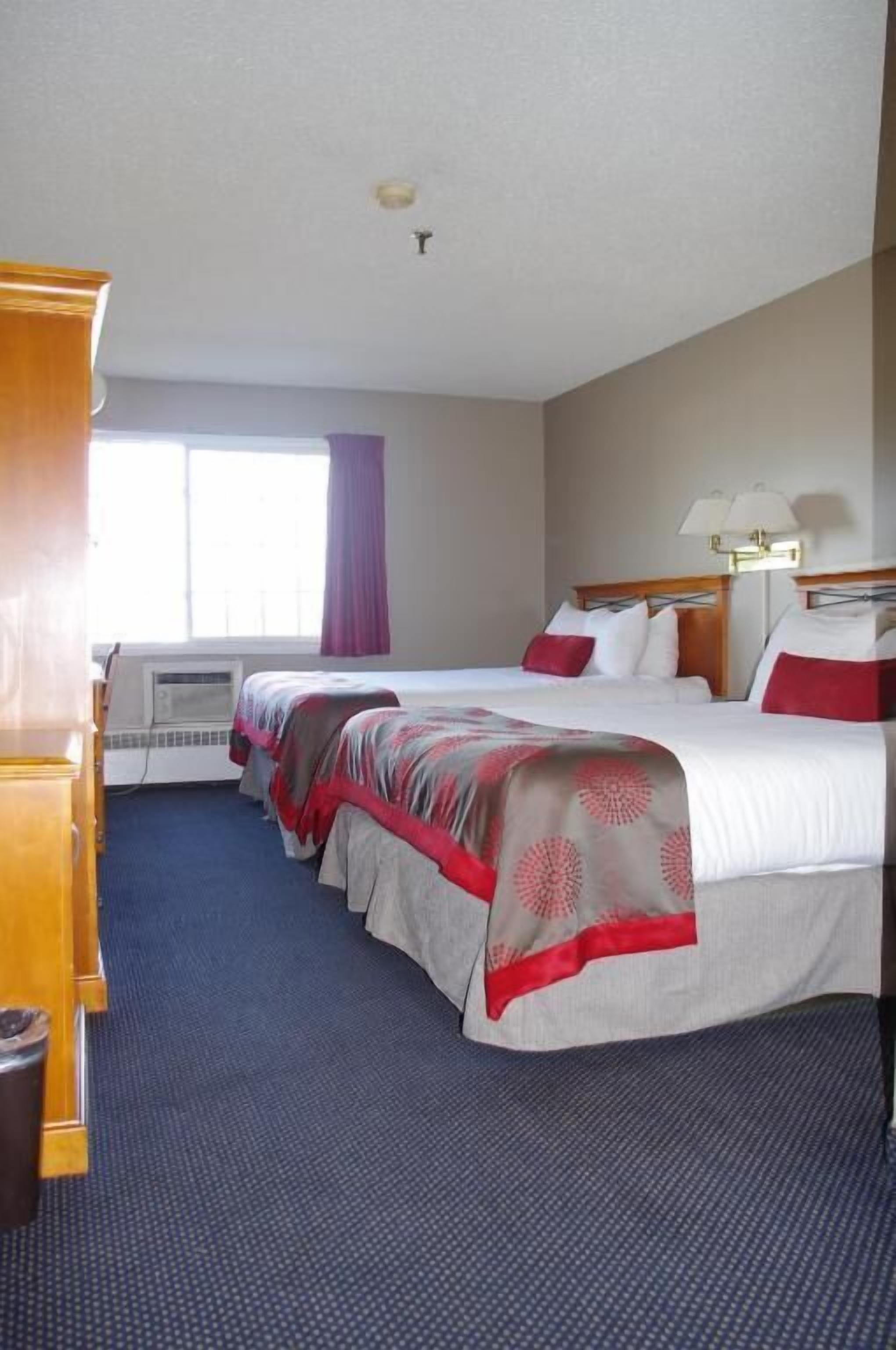A hotel room with a large bed, a desk, and a window with curtains.