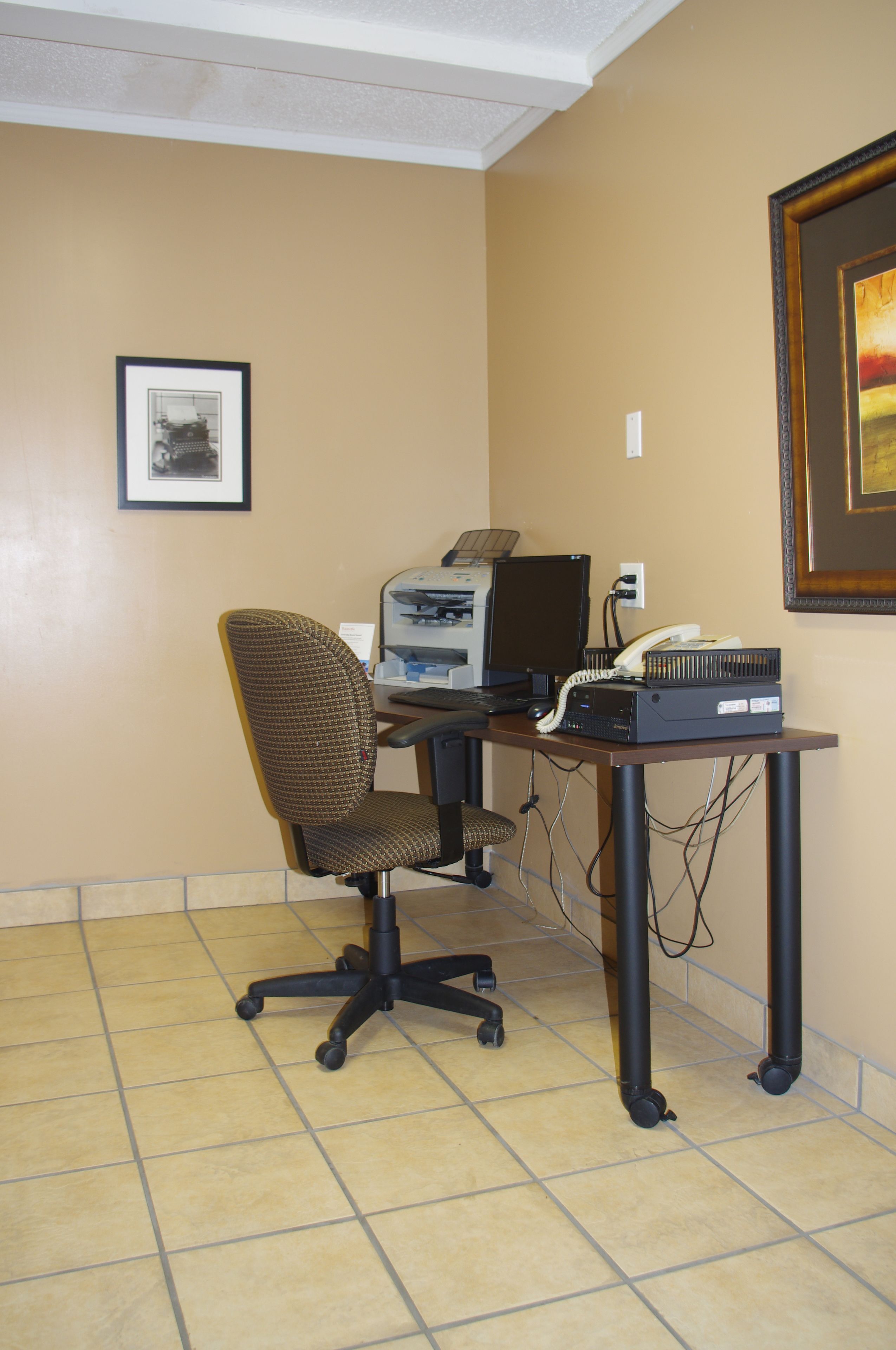A small office space with a desk, computer, and chair.