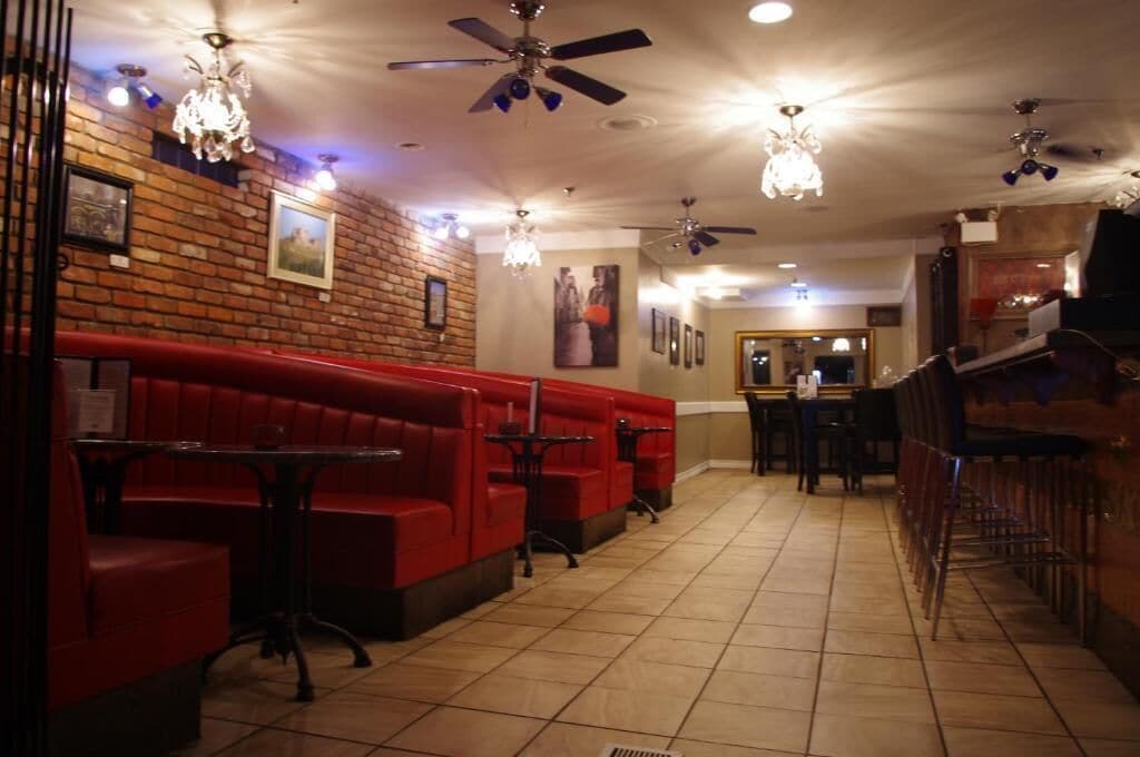 A restaurant with red booths, ceiling fans, and chandeliers.