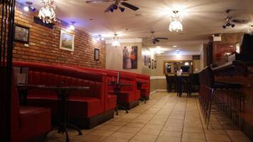 A restaurant with red booths, ceiling fans, and chandeliers.