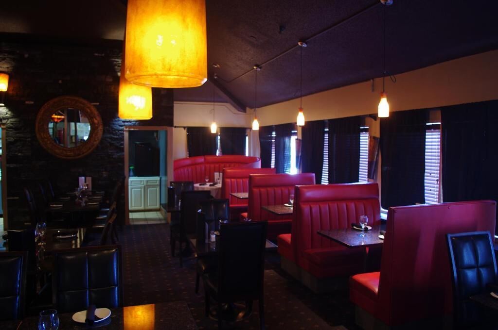En restaurang med avskilda bås och bord, dämpad belysning och en vägg av sten.