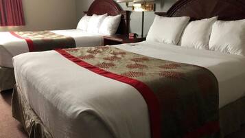 Une chambre d’hôtel avec deux lits, chacun agrémenté de draps blancs et d’une bordure décorative rouge. Il y a deux tables de chevet avec des lampes, ainsi qu’une lampe fixée au mur.