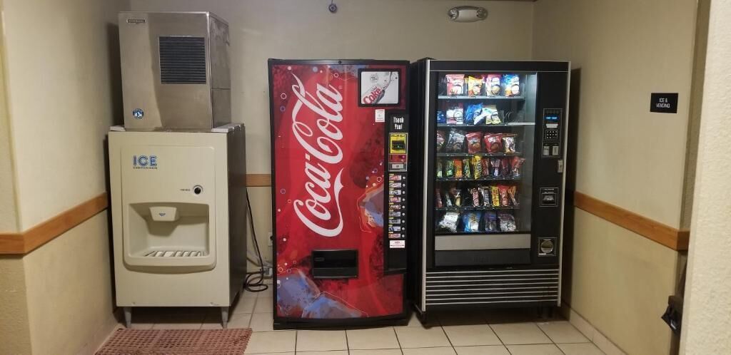 A vending machine with a Coca-Cola logo and a Coca-Cola branded refrigerator.