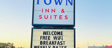 A sign for Home Town Inn & Suites with amenities including free WiFi, breakfast, and weekly rates.