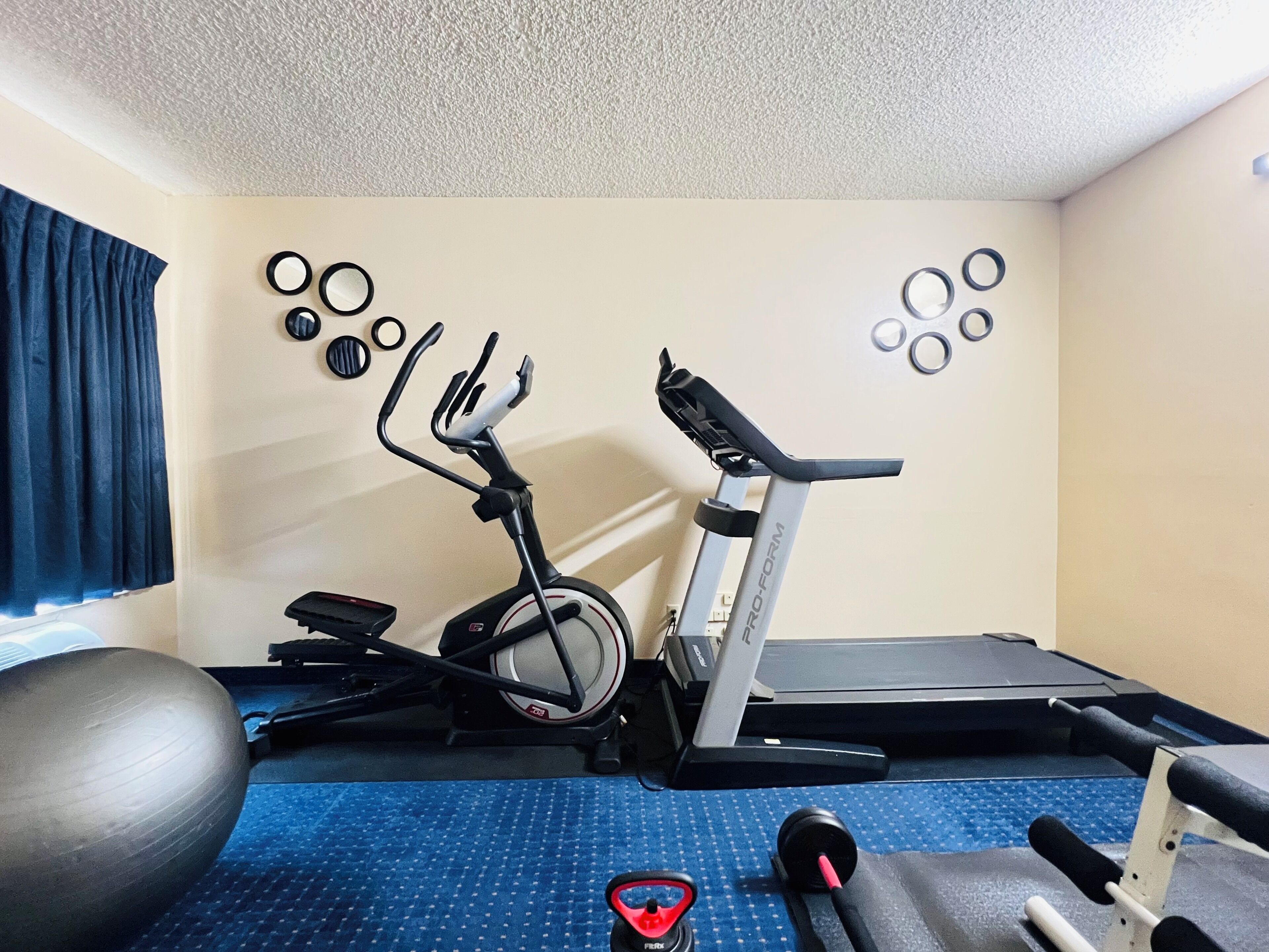 A home gym with an elliptical, a treadmill, and various exercise equipment.