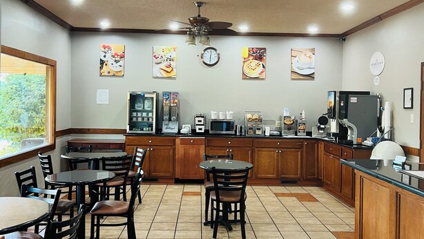 A spacious kitchen with wooden cabinets, a central island, and a dining area with chairs. - Hometown Inn & Suites (Washington)