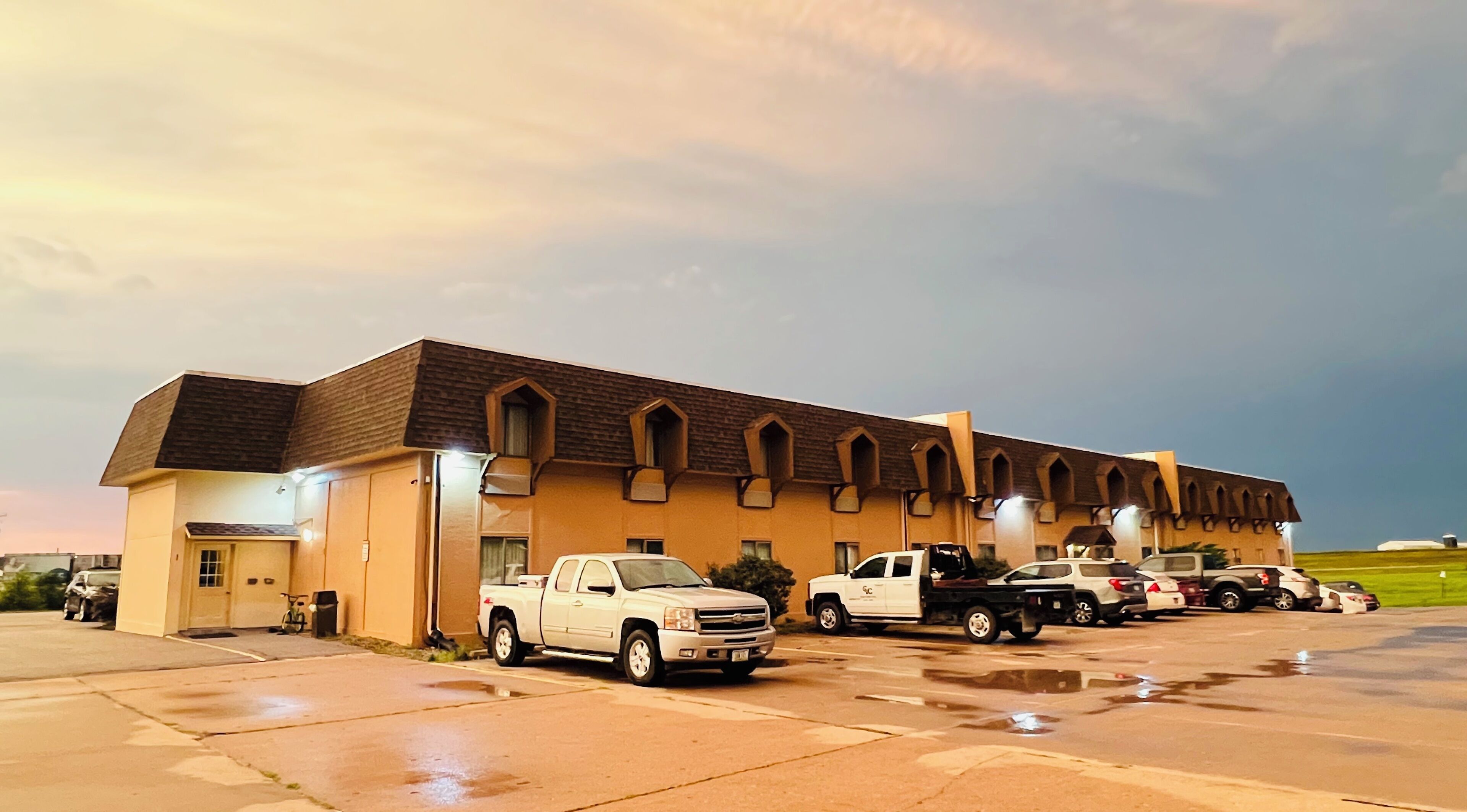 A building with a row of arched windows and a parking lot with several vehicles.