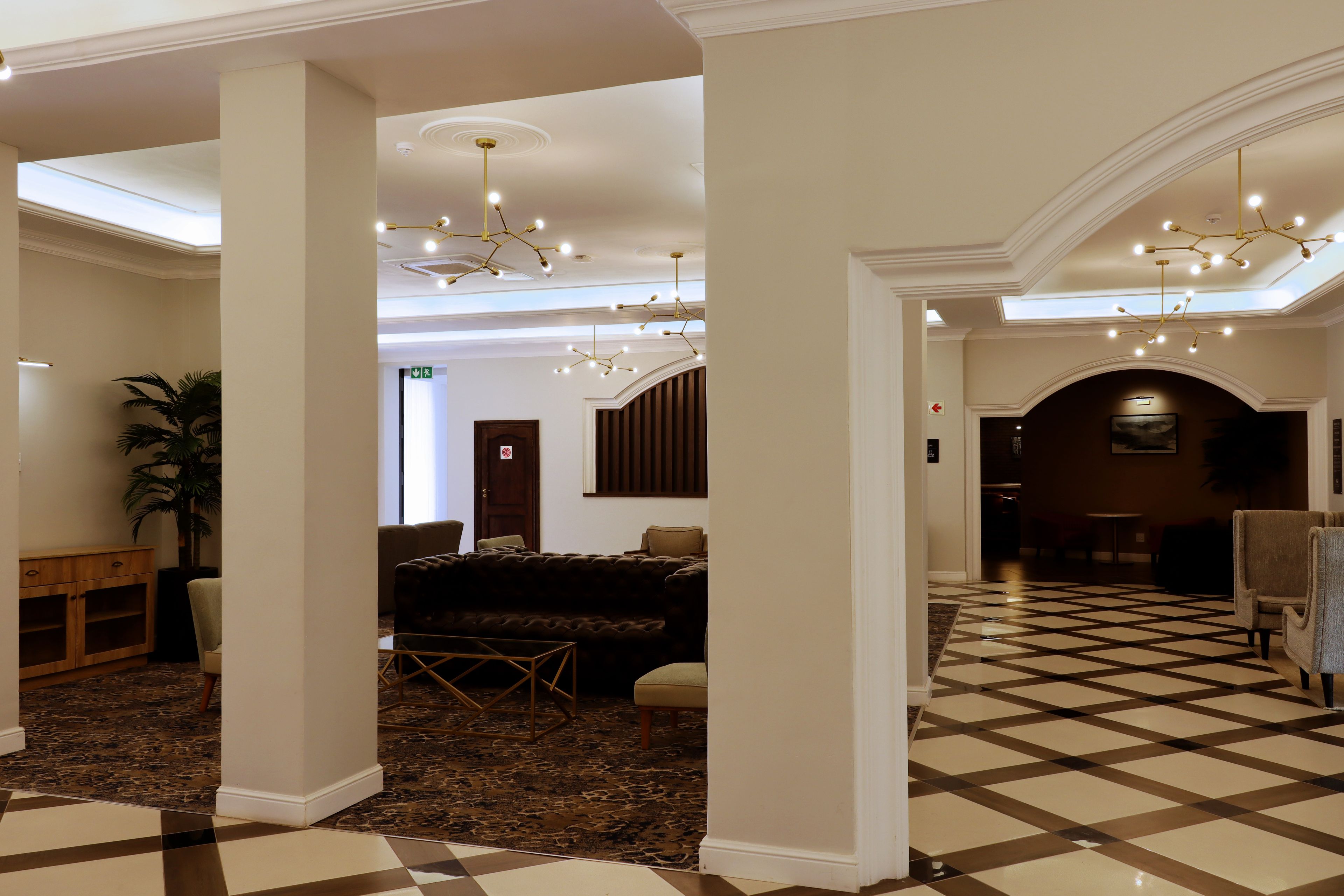 A hotel lobby with a checkered floor, a sofa, a coffee table, and a chandelier.