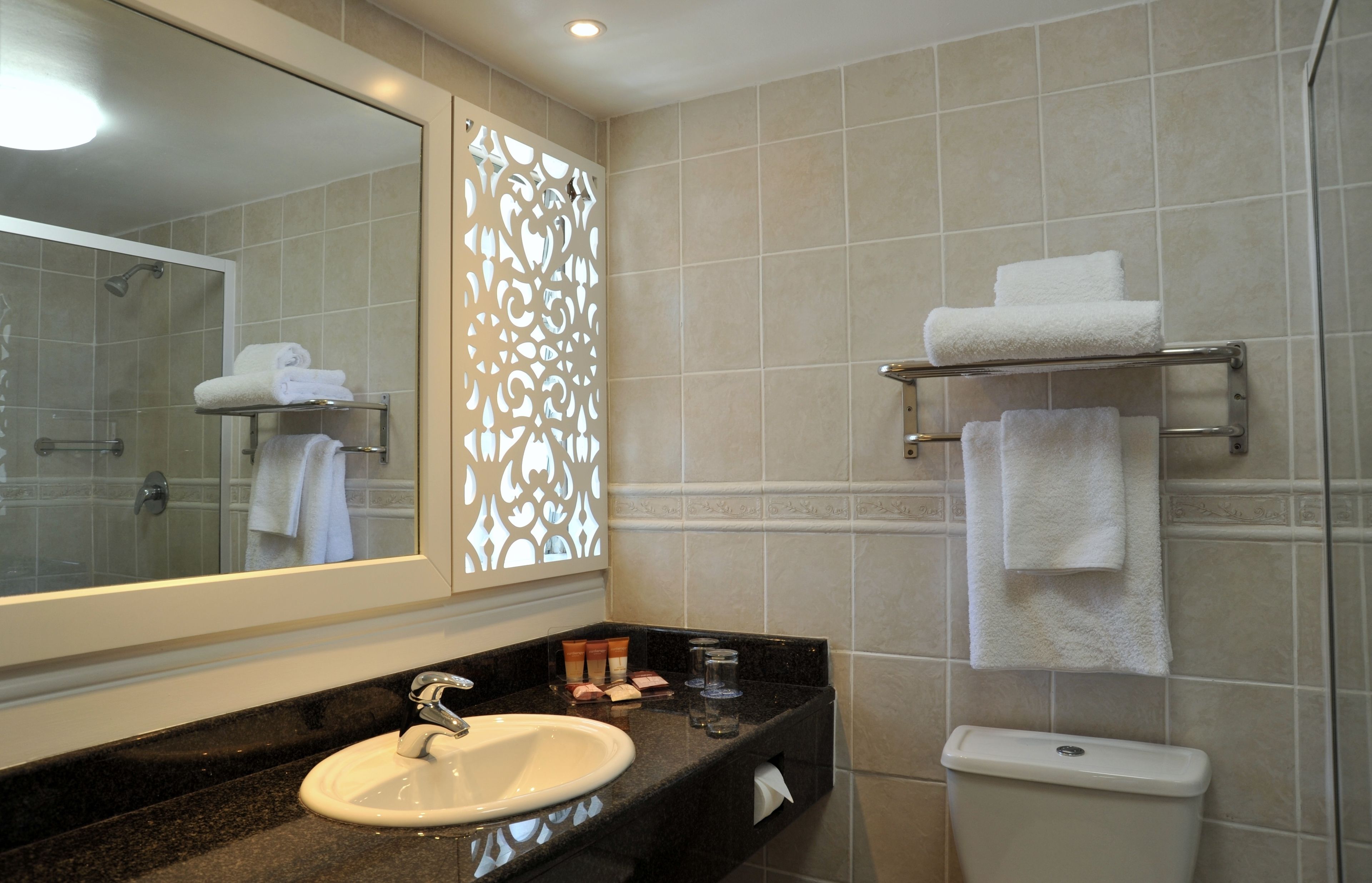 A bathroom with a sink, mirror, shower, and towel rack.